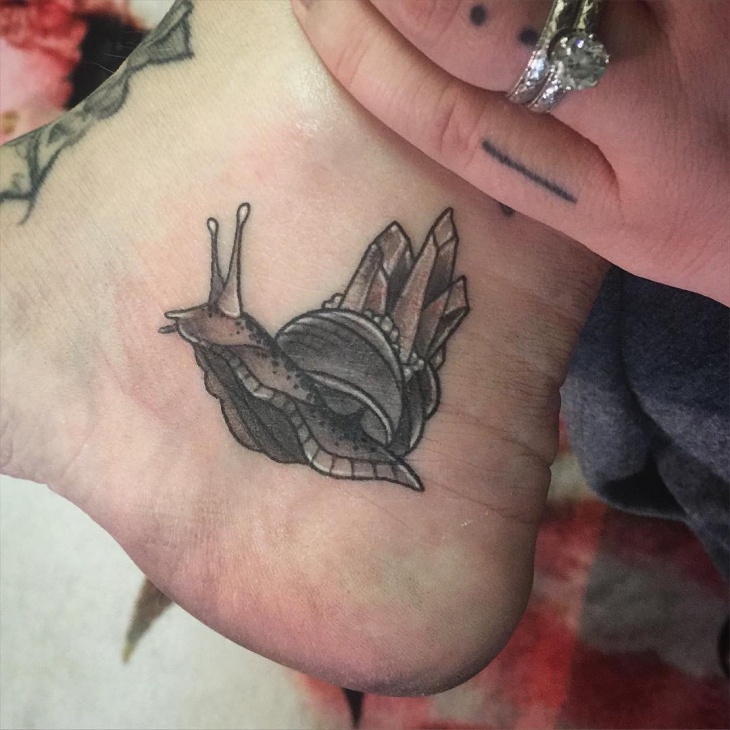 small snail tattoo on ankle