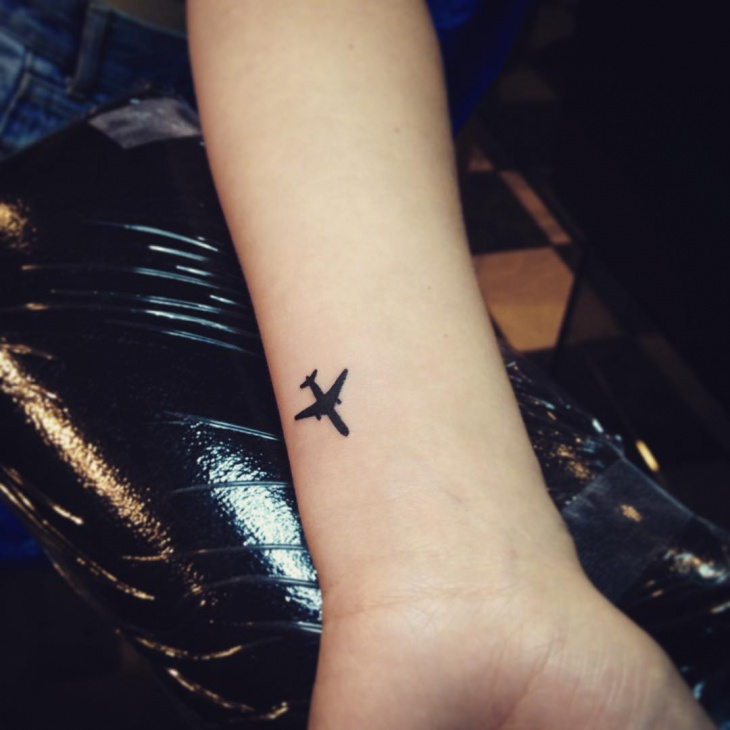small airplane tattoo on wrist
