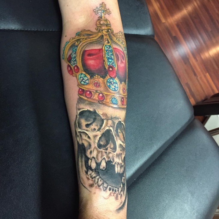 skull with crown tattoo on forearm